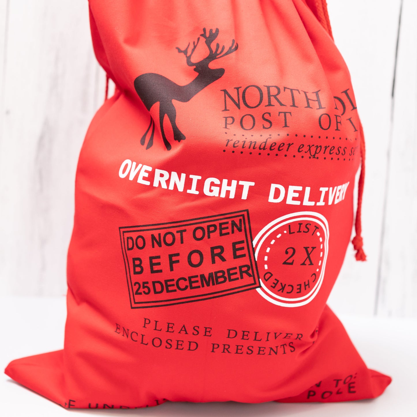 Christmas Gift Bags | Reusable Oversized Fabric with Drawstring Cord - North Pole Post Office Overnight Delivery Logo